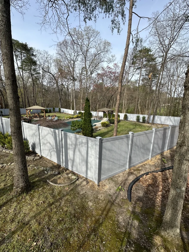 New white privacy fence installed around landscaped backyard with pool and trees